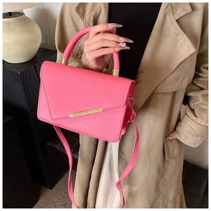 Close-up of pink crossbody bag with litchi texture and gold metal hardware detail