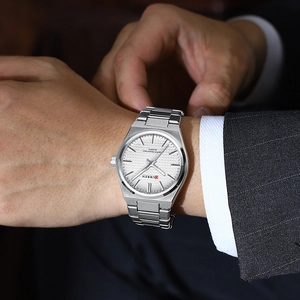 Close-up of men's silver business watch with white textured dial on suit sleeve