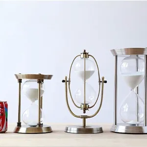Three metal hourglass timers in vintage bronze and silver styles with white sand