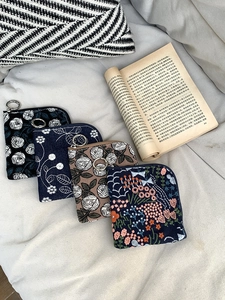 Detail view of four linen coin purses with floral embroidery and metal zippers