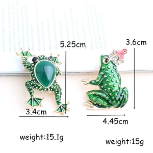 Cartoon frog brooches with green rhinestones and gold crown details on paper
