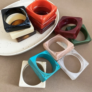 Modern square acrylic bangles with marble texture in multiple colors on a ceramic tray