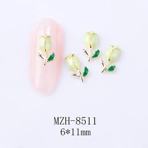 Macro shot of 6x11mm green tulip nail charms with gold edges on a pink nail tip