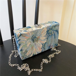 Detail of blue floral jacquard fabric texture and silver chain on rectangular clutch