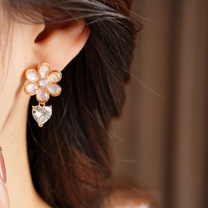 Detailed view of resin flower earrings with heart zircon pendants worn on a model
