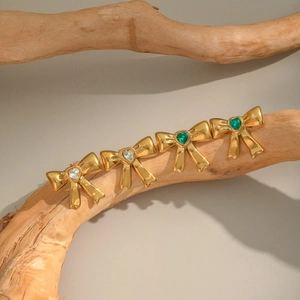 Golden bow earrings with heart-shaped zircons in white and emerald green finish