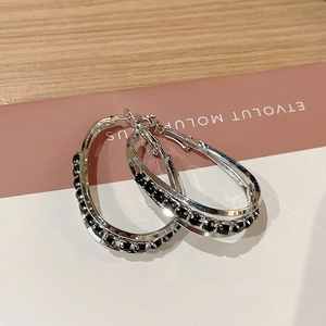Macro detail of silver double-layered oval hoop earrings with micro-set black zircons