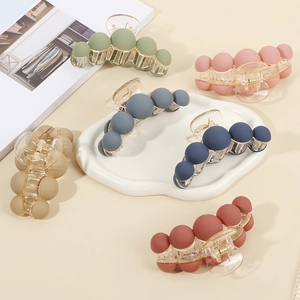 Matte ball hair claw clips in various muted colors displayed on a ceramic tray