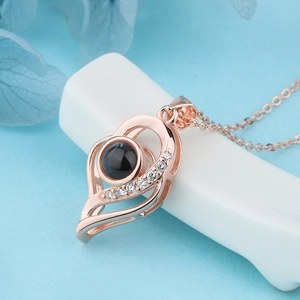 Macro detail of rose gold heart projection necklace with small diamonds on a blue background