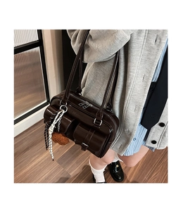 Detail of dark brown vintage bowling bag with front pockets and fluffy bag charm accessory