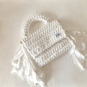 Detail of white handmade crochet bag featuring thick fringe and textured fabric weave