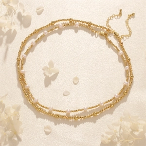 Double-layered gold beaded necklace with white freshwater pearls and lobster clasp