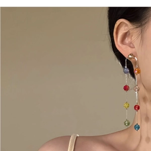 Close-up of colorful glass bead tassel earrings worn by a model in soft lighting