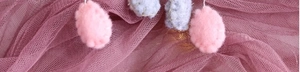 Detail of handmade felt hanging ornaments showing soft pink texture and white stitching