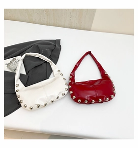 Flat lay of white and red tote bags featuring large silver metallic rivets and studs