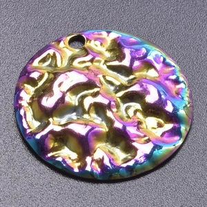 Macro view of round rainbow plated stainless steel pendant with hammered molten texture