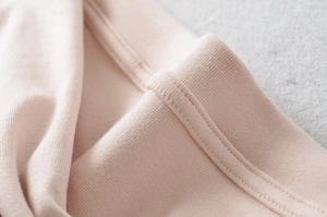 Close-up of pink ribbed knit fabric texture and neat stitching on long sleeve top
