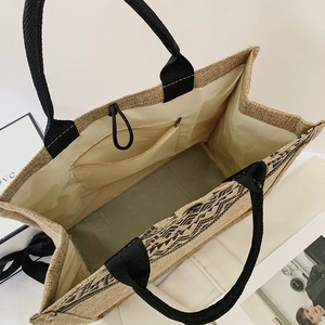Detail view of large jute tote bag showing internal zipper pocket and drawstrings