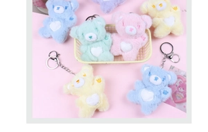 Close-up of colorful plush bear keychains with white heart motifs in a pastel basket