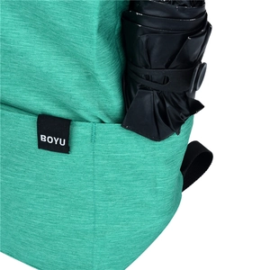 Green canvas backpack side pocket detail with black folding umbrella stored inside