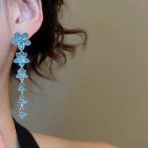 Macro shot of elegant long floral tassel earrings featuring vibrant blue zircon stones