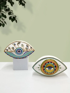 Close-up of ceramic evil eye storage trays with colorful mandala patterns on white surface