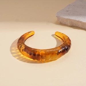 Macro shot of amber tortoiseshell acrylic cuff bracelet with natural stone details
