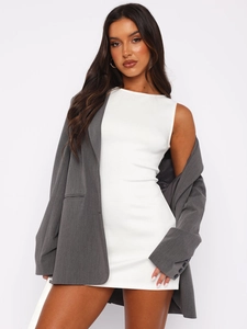 Détail d'une robe blanche sans manches avec un blazer gris pour un look de bureau moderne
