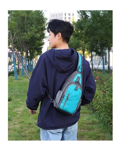 Teal waterproof nylon crossbody chest bag shown on model in an outdoor park setting
