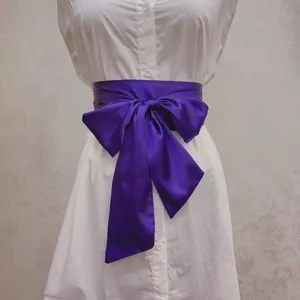 Ceinture obi élégante en satin violet avec grand nœud sur une chemise blanche femme
