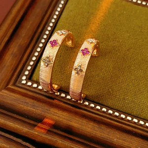 Macro shot of rose gold C-shaped earrings with purple flower gemstones on green velvet