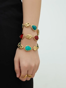 Detail of 18k gold plated bracelets and rings with colorful resin inlay on wrist