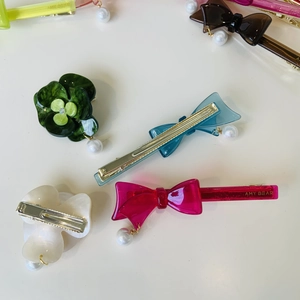 Assorted acetate bow and flower hair clips with pearls on a clean white background