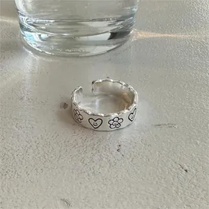 Macro view of sterling silver open ring with smiling flower and heart patterns