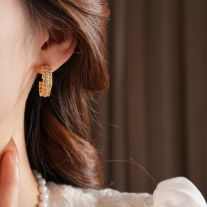 Close-up of elegant 18k gold plated C-shaped earrings with rhinestones on a model