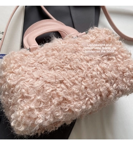 Detail view of pink faux wool texture and smooth leather strap on a box-style handbag