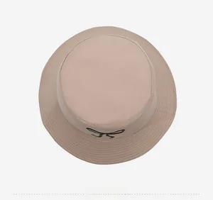 Top down view of embroidered bow detail on beige cotton sun hat with stitched brim