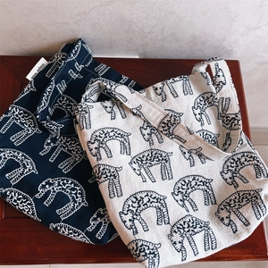 Close-up of embroidered canvas mini bags in navy and cream with sheep patterns