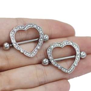 Detailed view of silver heart-shaped nipple ring with clear zircons held in hand