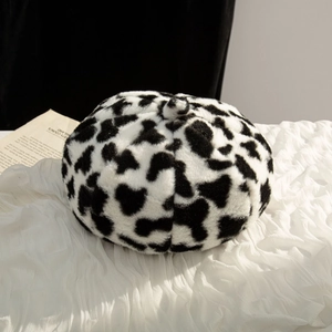 Close-up of soft plush cow print beret hat showing thick faux fur texture and pattern
