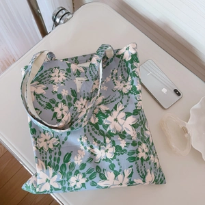 Detail of floral tote bag with blue base and white flower pattern on a white desk
