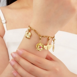 Goldenes Armband aus Titanstahl mit Blumen- und Ginkgoblatt-Anhängern am Handgelenk