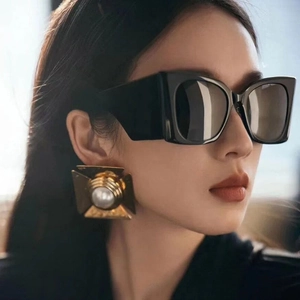 Übergroße quadratische Sonnenbrille mit schwarzem Rahmen und dunklen Gläsern am Modell