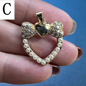 Detail of a heart-shaped pearl pendant with a gold bow and cubic zirconia accents