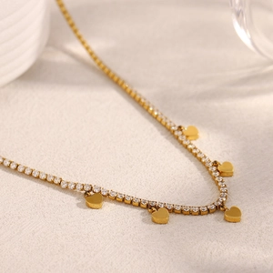 Gros plan du collier avec pendentif cœur en acier inoxydable doré et zircons brillants