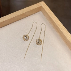 Detailed view of gold flower earrings with crystals on a wooden jewelry display