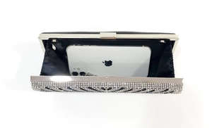 Detail of black rhinestone evening clutch with wave pattern and chain strap, showing phone capacity
