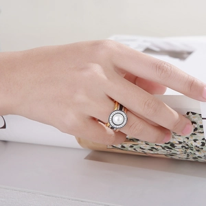 Detail of layered titanium steel ring with shell pearl and rhinestones worn on finger