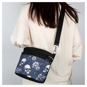 Vue détaillée du sac à bandoulière noir avec imprimé crâne et fleurs sur le dos d'un mannequin