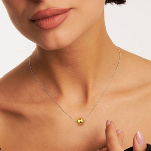 Minimalist stainless steel mixed-tone necklace with golden sphere pendant on female model
